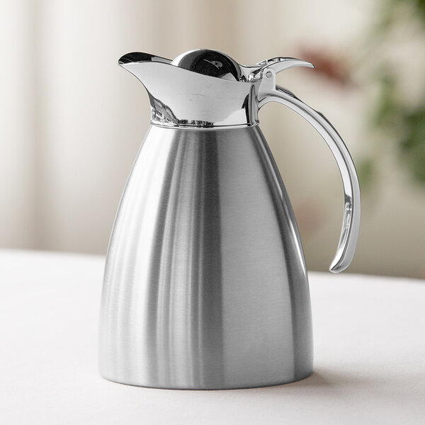 A brushed stainless steel insulated carafe with a flip-top lid and handle.
