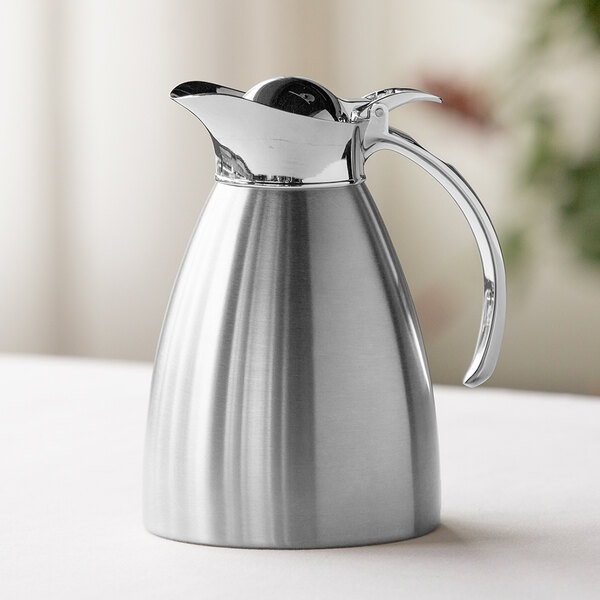 A brushed stainless steel insulated carafe with a flip-top lid and handle.