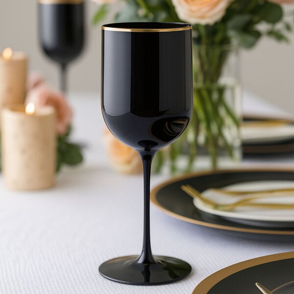 A black plastic wine goblet with a gold rim, placed on a formal dining table.