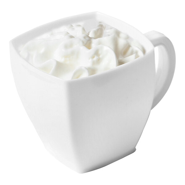 A white square-shaped disposable plastic coffee mug filled with a creamy beverage.
