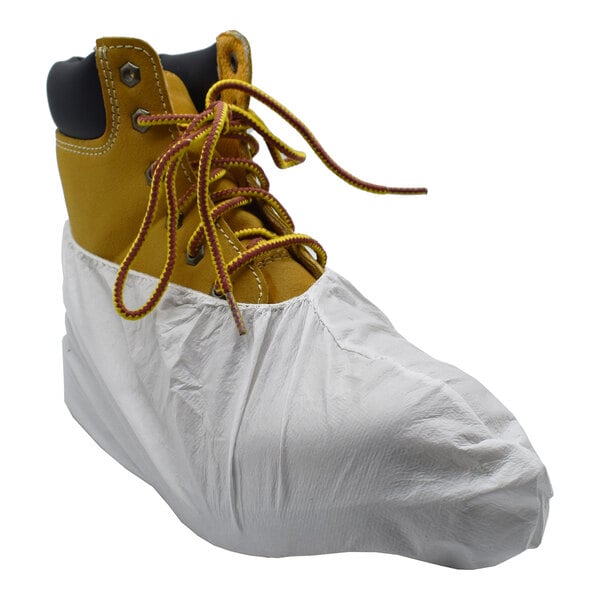 A yellow work boot partially covered by a white disposable microporous shoe cover.