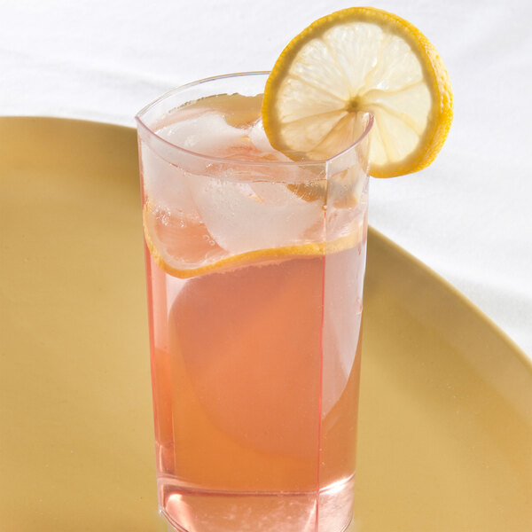 A clear 12 oz. triangle-shaped polystyrene tumbler filled with a pink beverage, ice, and garnished with a lemon slice.