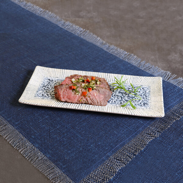 A rectangular light blue melamine platter with a textured design, shown with a serving of steak and garnish.