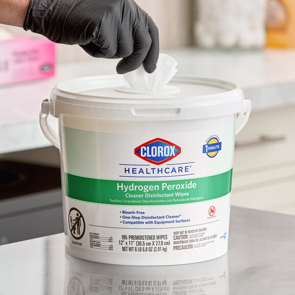 A container of Clorox Healthcare hydrogen peroxide cleaner disinfectant wipes with a person pulling out a wipe.
