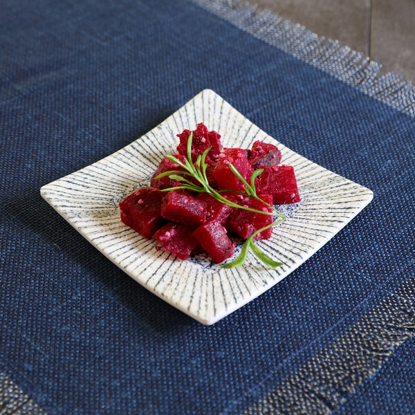 A square light blue melamine plate with a serving of cubed red beets garnished with herbs.