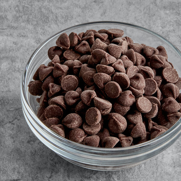 A glass bowl filled with dark chocolate and peppermint baking chips.