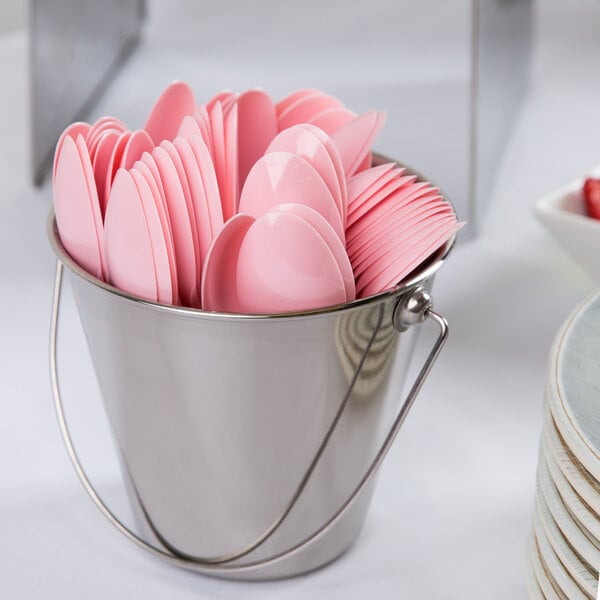 A metal bucket filled with pink heavy weight plastic spoons.