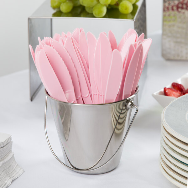 A small metal bucket filled with pink plastic knives.