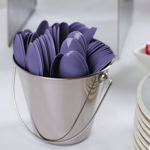 A metal bucket filled with purple heavy weight plastic spoons.