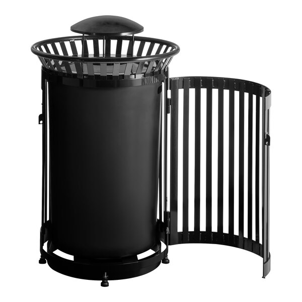 A large round black steel outdoor trash can with a slatted design, rain bonnet lid, and a side door.
