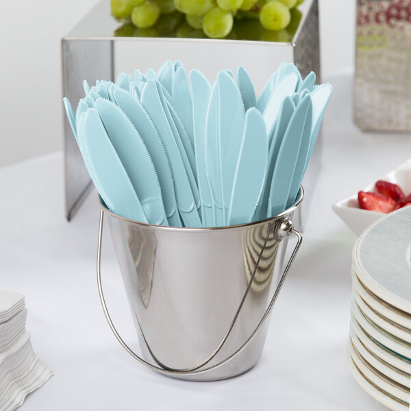 A small metal bucket filled with pastel blue heavy weight plastic knives.