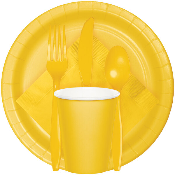 A set of yellow disposable tableware including a plate, cup, napkin, fork, knife, and spoon.