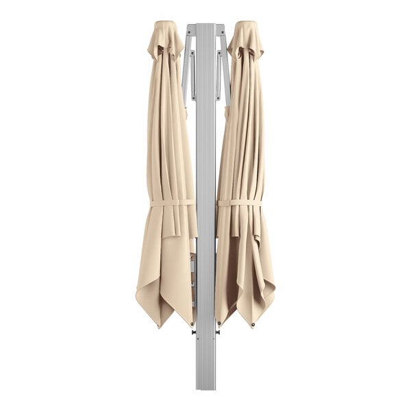 A twin cantilever umbrella with a silver aluminum frame and sand-colored fabric, shown closed.
