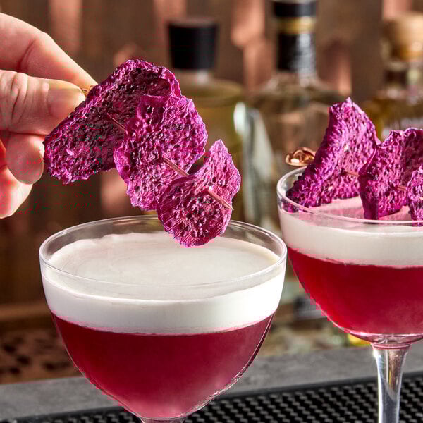 A set of dried dragon fruit slices used as garnish for cocktails or beverages.