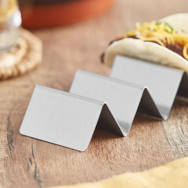 A stainless steel mini taco holder with three compartments for holding tacos upright.
