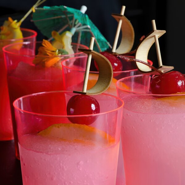 A row of Fineline Savvi Serve tall neon red plastic tumblers filled with pink drinks, each garnished with a cherry.