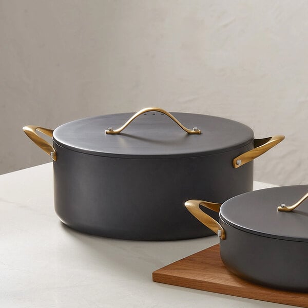 A black round induction-ready casserole pan with a cover and gold handles.