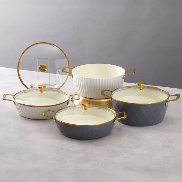 A set of round induction-ready casserole pans with covers, featuring graphite and white colors with gold handles and accents.