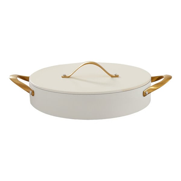 A round ivory casserole pan with a lid and gold-colored handles.