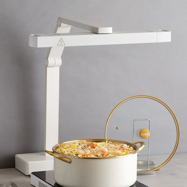 A white multi-position infrared heat lamp positioned above a pot of food.