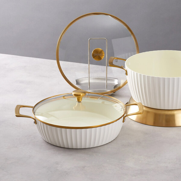A white round induction-ready casserole pan with a glass cover and gold accents.