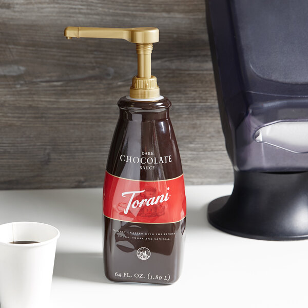A Torani dark chocolate sauce bottle with a gold pump dispenser designed for 64 fl. oz. bottles.