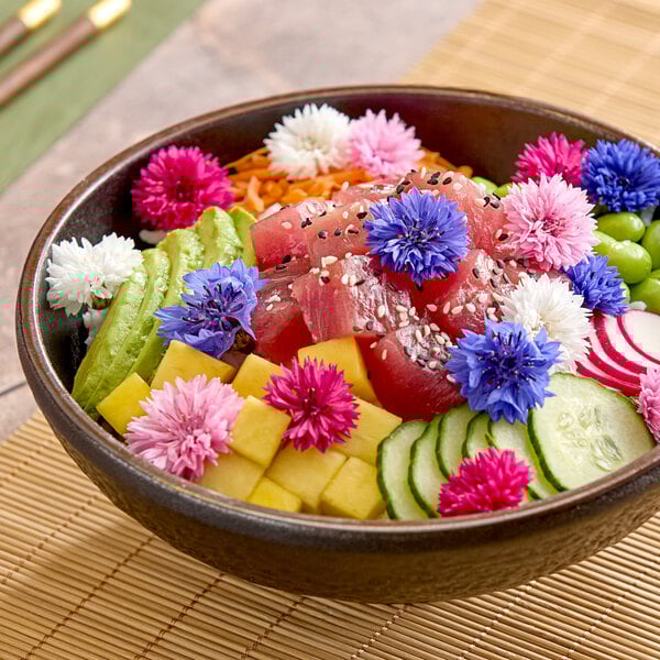 A bowl of poke topped with colorful Fresh Origins Bachelor's Button edible flowers, sliced vegetables, and diced fruit.