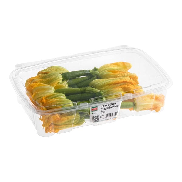 A plastic container of fresh zucchini with edible flowers.