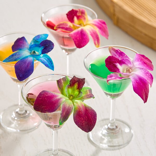 A set of colorful cocktails each garnished with a multi-colored edible orchid flower.