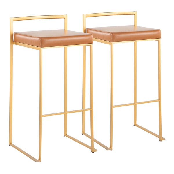 A pair of gold steel barstools with low backs and camel faux leather seats.