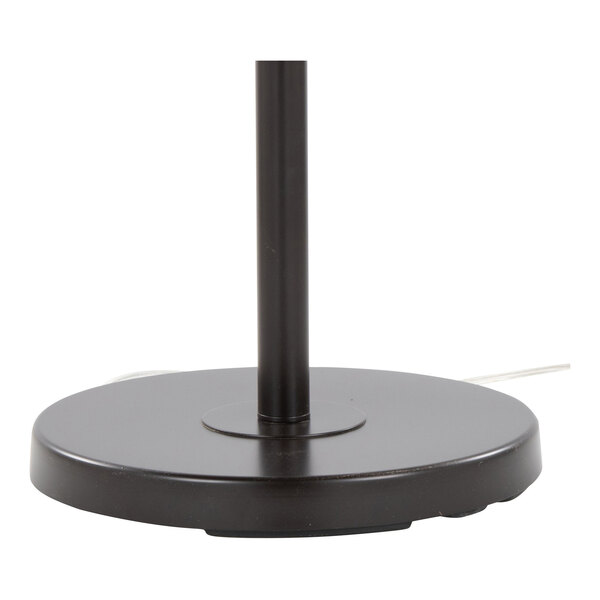 A round oil bronze metal base of a floor lamp with a vertical pole and a visible power cord.