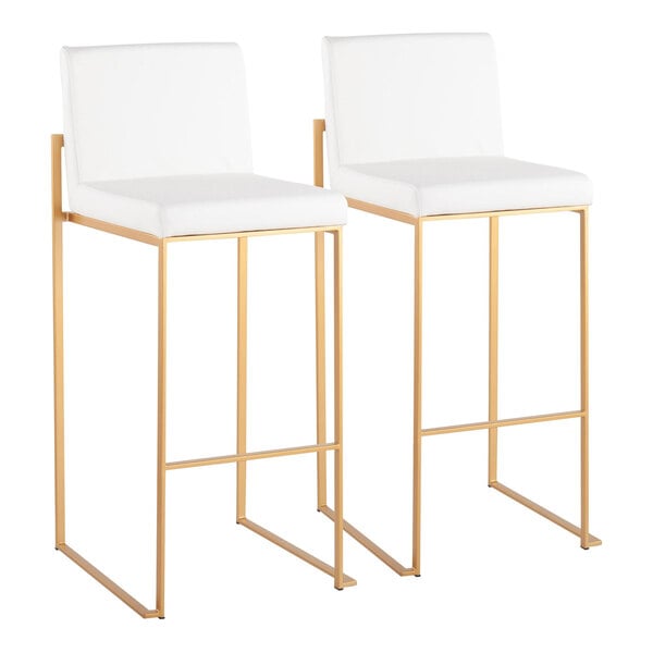 A pair of high back barstools with white faux leather seats and gold steel frames.