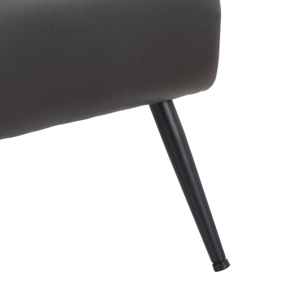 A close-up of a black metal leg and part of the espresso faux leather seat of an accent chair.