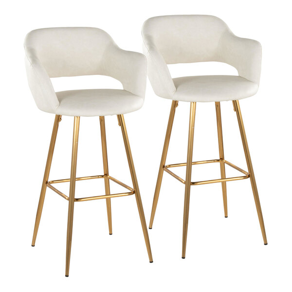 A pair of barstools with cream faux leather bucket seats, armrests, and gold metal legs.
