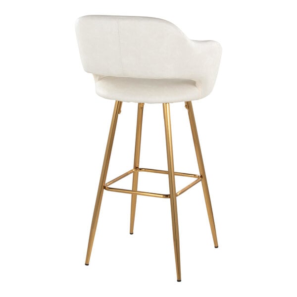 A barstool with a cream faux leather bucket seat, armrests, and gold metal legs.