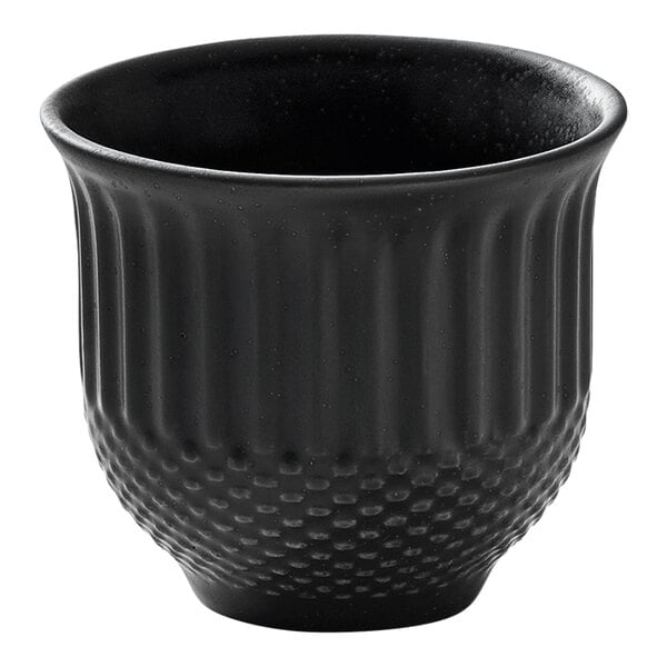 A small, round, black porcelain cup with a textured exterior.