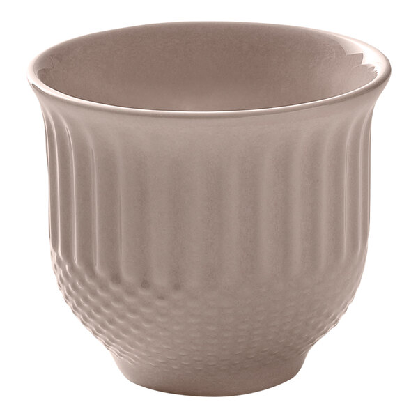 A small round blush-colored porcelain cup with a textured exterior.