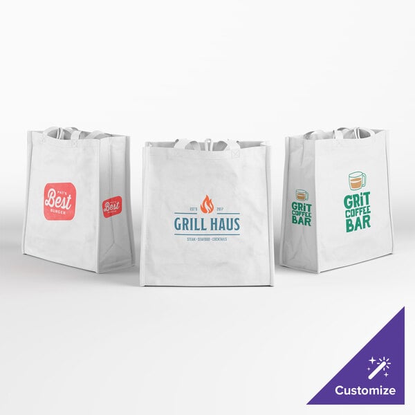 Three white reusable shopping bags are displayed, each featuring a different colorful printed logo and text on the front, with handles visible at the top.
