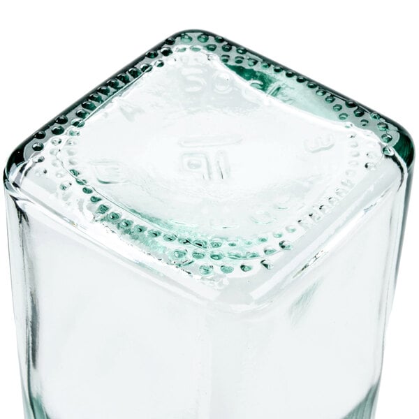 A clear, square glass olive oil cruet.
