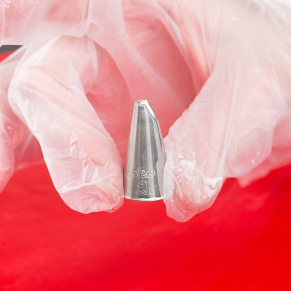 A metal Ateco Lily-of-the-Valley piping tip held by a gloved hand.