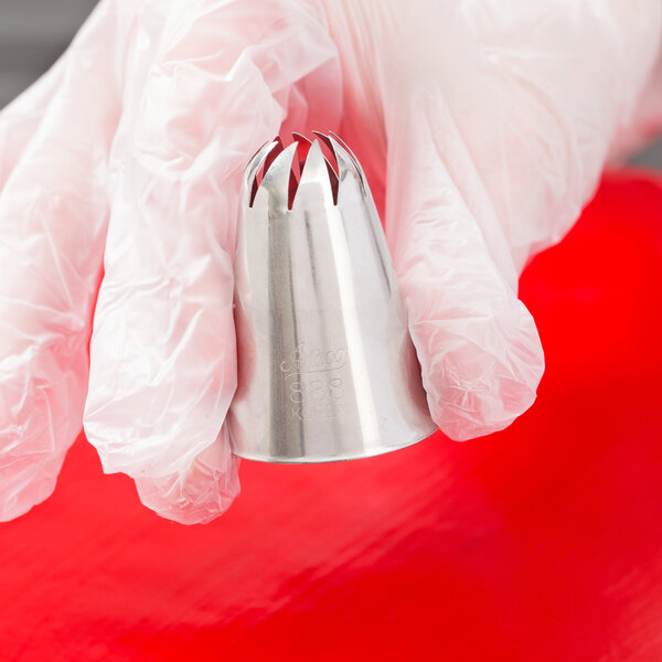 A stainless steel swirl top piping tip held by a gloved hand.