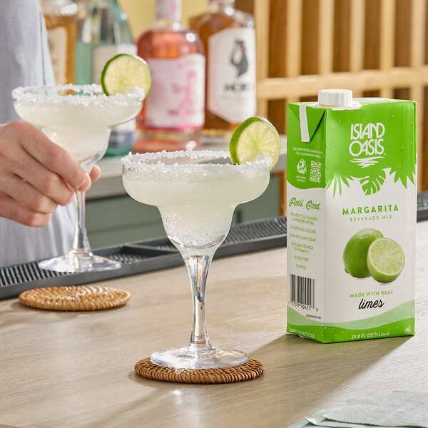 A carton of Island Oasis Margarita Beverage Mix, 1 liter, displayed next to a margarita glass with a salted rim and lime garnish.