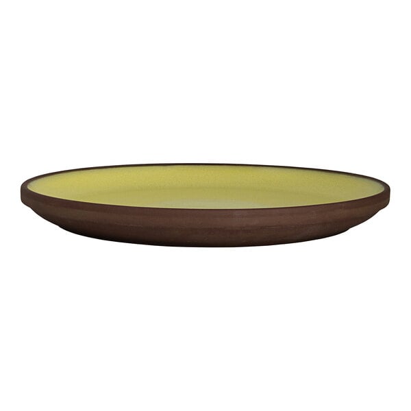A round stoneware plate with a brown exterior and a saffron yellow interior.