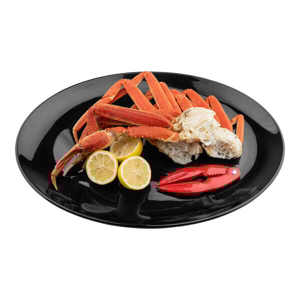 An oval black melamine serving platter holding crab legs, lemon slices, and a red seafood cracker.