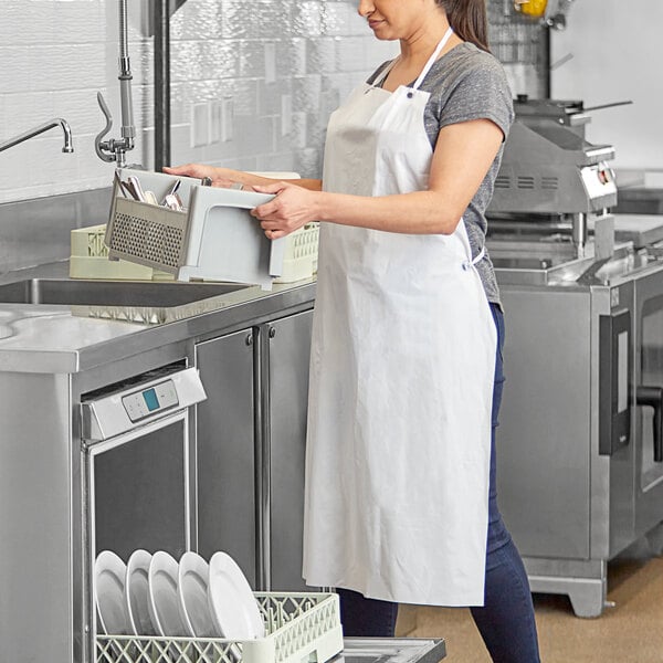 A person wearing a white lightweight vinyl dishwasher apron while working in a commercial kitchen.