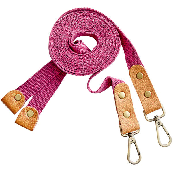 A pair of pink cross-back replacement straps with tan leather accents and metal clips.