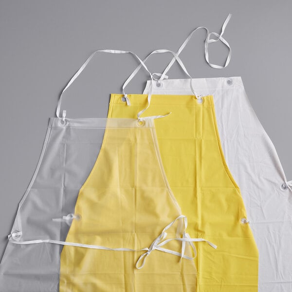 A set of three vinyl dishwasher aprons in clear, yellow, and white colors, each with white neck and waist ties.