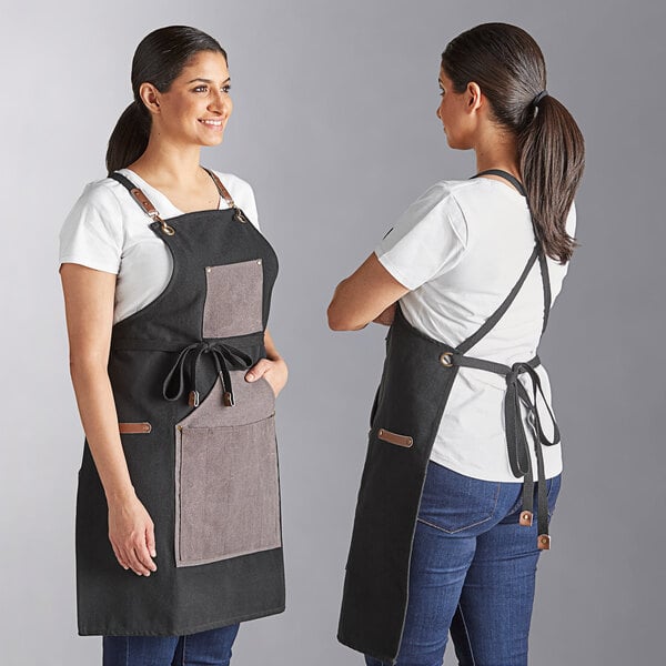 A black grilling apron with charcoal straps and large front pockets, shown from both the front and back.