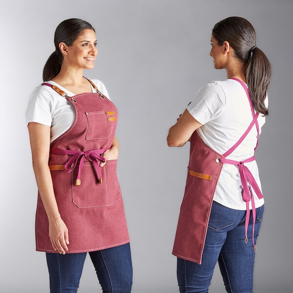 An Acopa Hazleton wine-colored heavy weight canvas cross-back bib apron with three pockets, shown from the front and back.