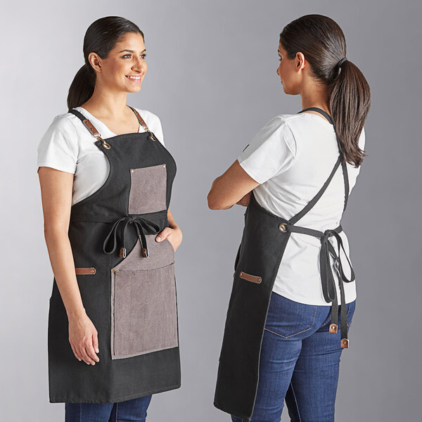 A charcoal heavy-duty canvas grilling apron with utility pockets, shown from the front and back.